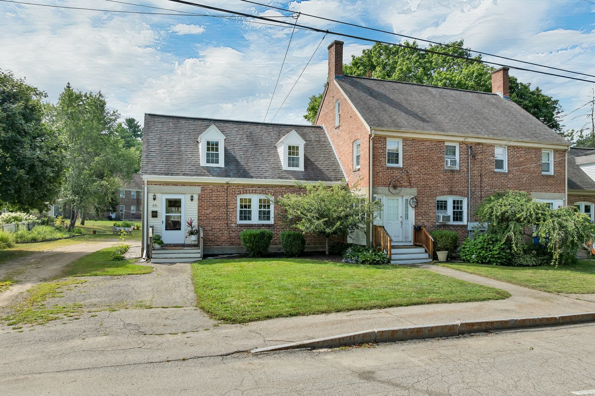 The brick two-family from the street corner, with both entrances and the front lawn