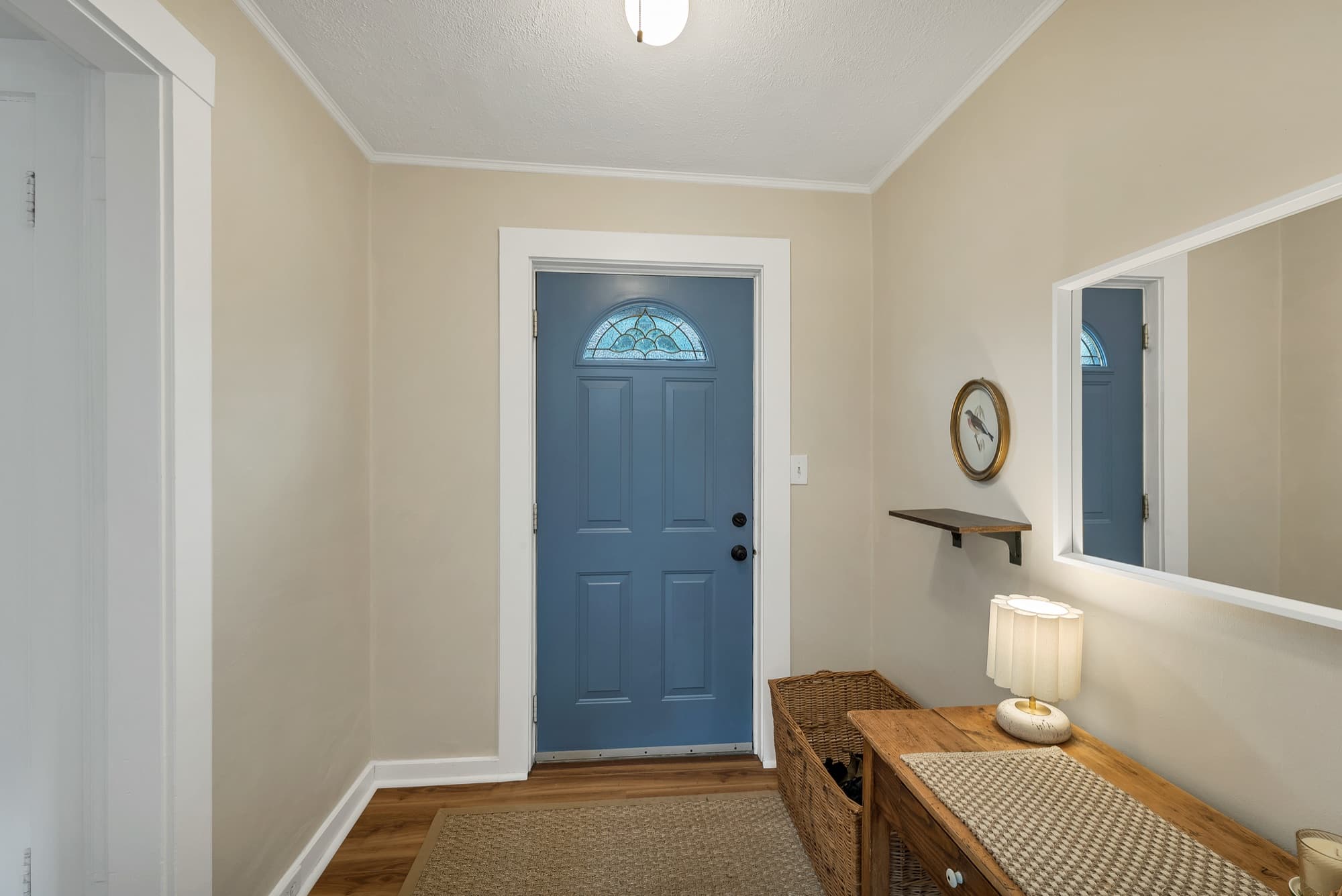 Unit 25 entry hall with a blue front door, mirror, and console table