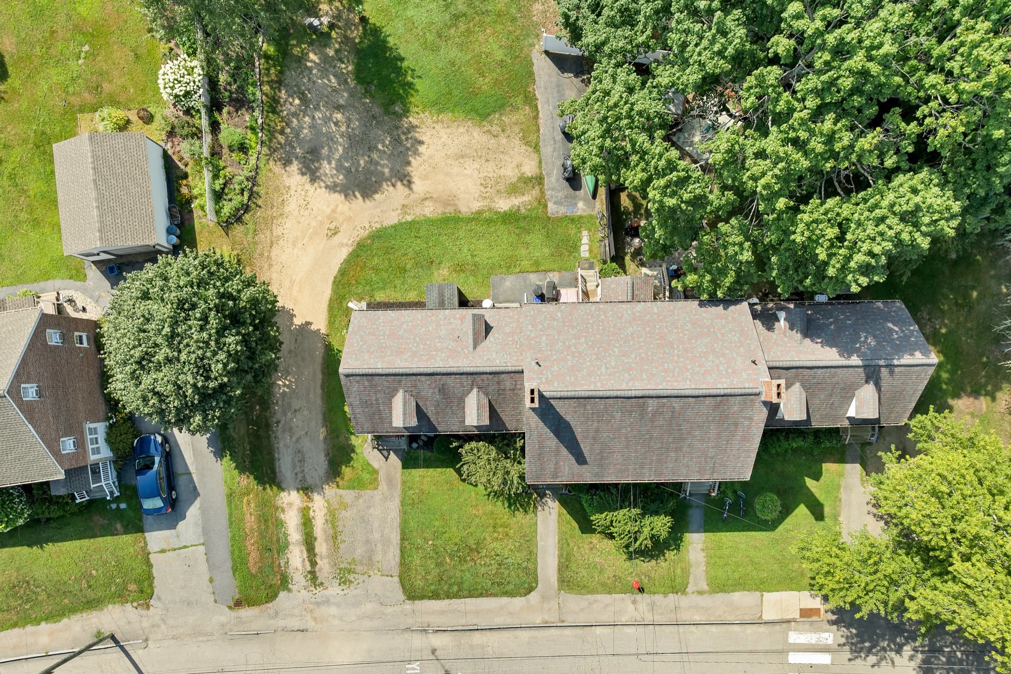 Aerial view straight down over the brick two-family, the drive, and the half acre lot